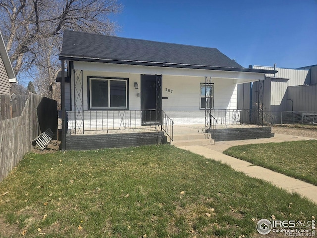 bungalow featuring a porch, fence, a front lawn, and roof with shingles