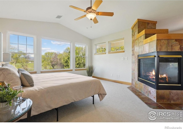 carpeted bedroom with vaulted ceiling, visible vents, a ceiling fan, baseboards, and a tiled fireplace