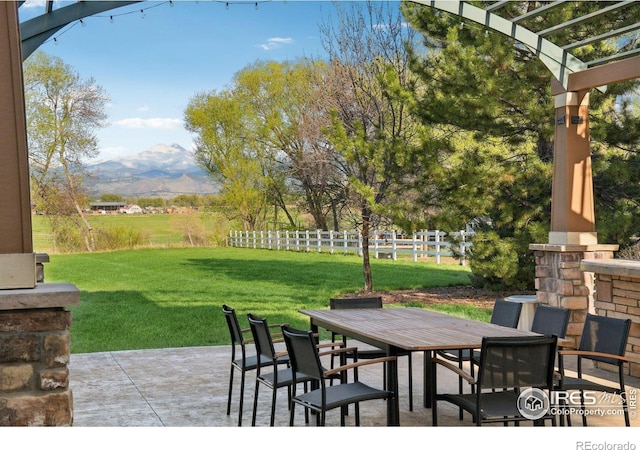 view of patio with fence, a pergola, a mountain view, and outdoor dining space