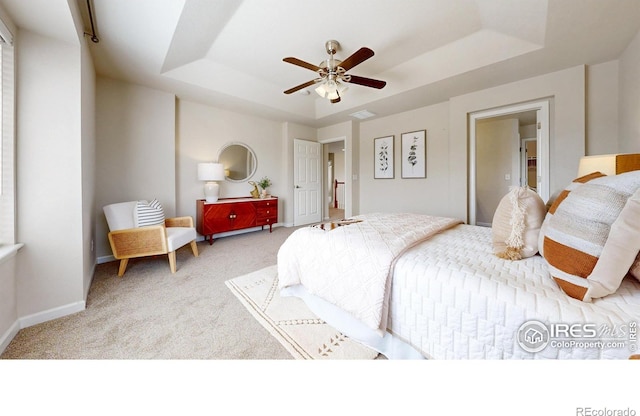 bedroom featuring carpet, visible vents, baseboards, and a raised ceiling