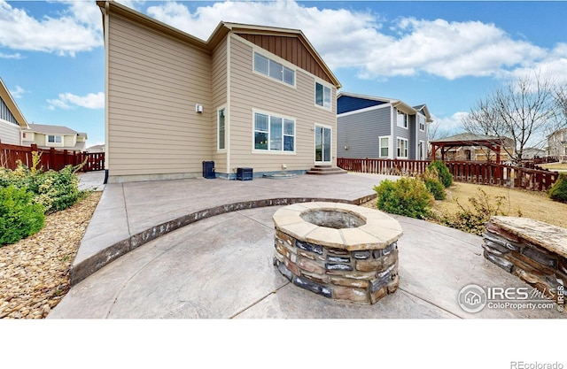 back of property with board and batten siding, a patio, fence, a fire pit, and a gazebo