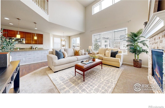 6748 Rainier Rd, Timnath, CO 80547 - living area with a fireplace, light wood-style flooring, a high ceiling, recessed lighting, and a chandelier