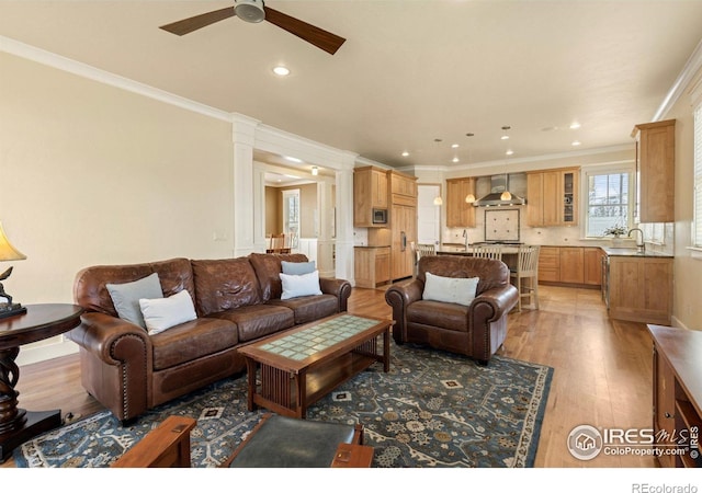 245 Spruce St, Louisville, CO 80027 - living room with crown molding, light wood finished floors, a ceiling fan, and ornate columns