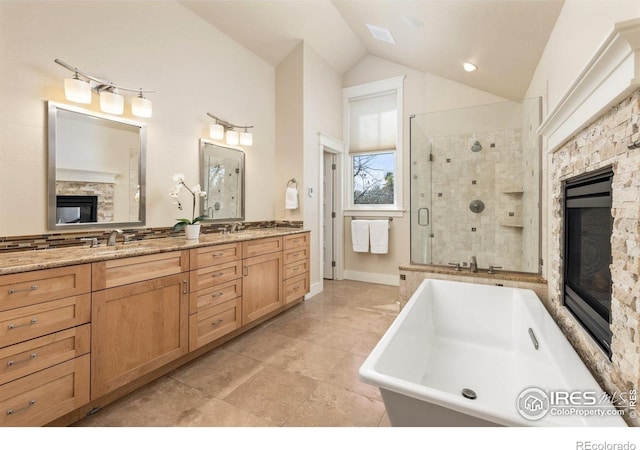 245 Spruce St, Louisville, CO 80027 - bathroom featuring a fireplace, lofted ceiling, a freestanding bath, a shower stall, and double vanity