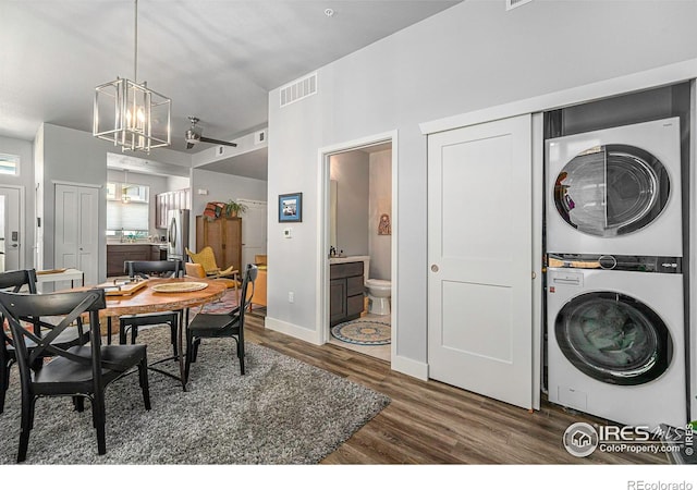 dining room featuring visible vents, baseboards, a chandelier, stacked washing maching and dryer, and wood finished floors