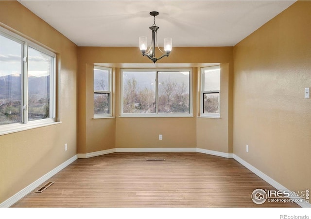 1458 Friendship Ln W, Colorado Springs, CO 80904 - empty room with visible vents, baseboards, an inviting chandelier, and wood finished floors