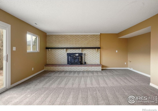 1458 Friendship Ln W, Colorado Springs, CO 80904 - unfurnished living room featuring a wood stove, carpet floors, baseboards, and a textured ceiling