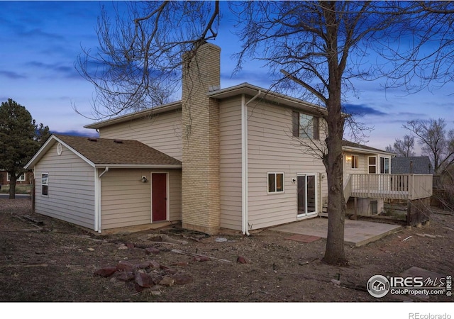 1458 Friendship Ln W, Colorado Springs, CO 80904 - back of house at dusk with a patio and a chimney