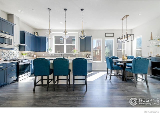 kitchen featuring light countertops, stainless steel appliances, blue cabinets, and dark wood-type flooring