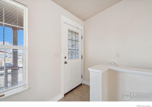 doorway with light tile patterned floors and baseboards