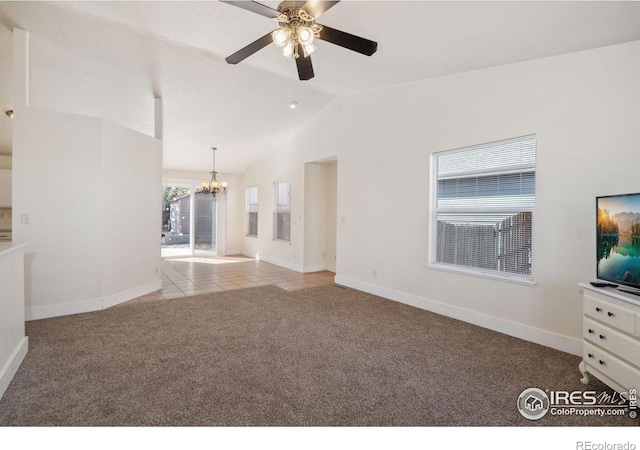 unfurnished living room featuring ceiling fan with notable chandelier, baseboards, vaulted ceiling, and carpet floors