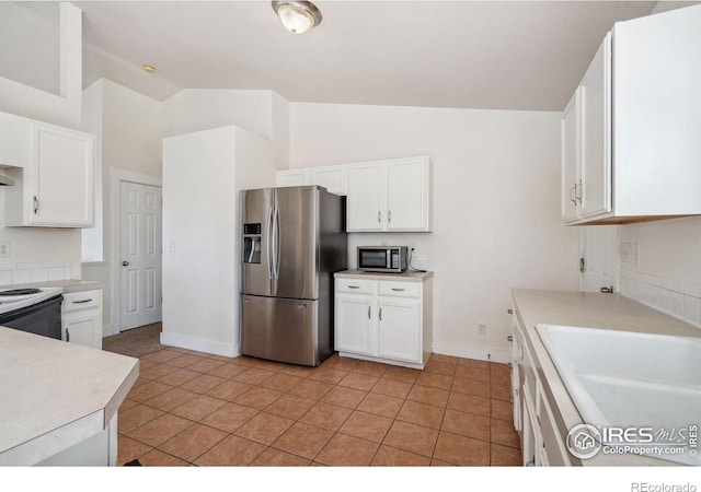 kitchen featuring white cabinets, appliances with stainless steel finishes, a sink, and vaulted ceiling