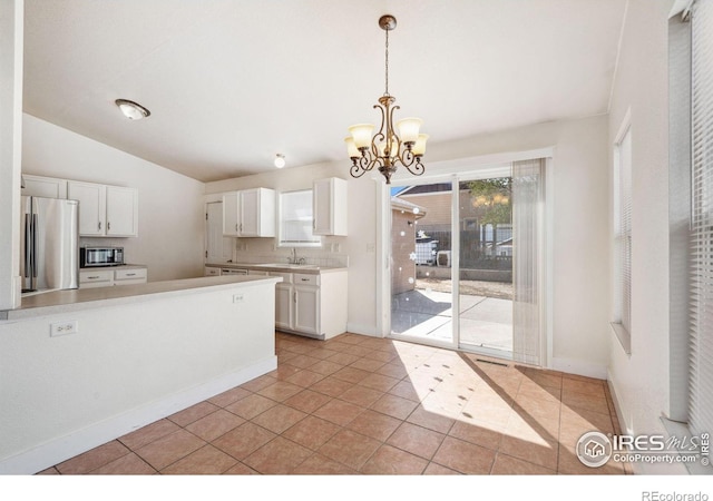 kitchen featuring white cabinets, an inviting chandelier, a sink, appliances with stainless steel finishes, and pendant lighting