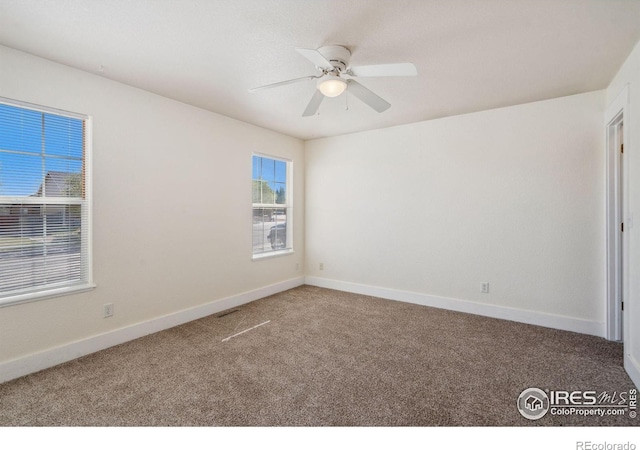 carpeted spare room with baseboards and a ceiling fan