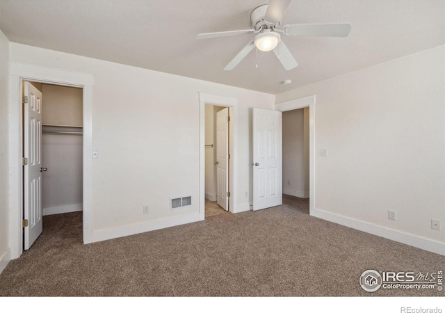 unfurnished bedroom with a spacious closet, baseboards, carpet, and visible vents