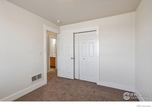 unfurnished bedroom with a closet, carpet flooring, visible vents, and baseboards