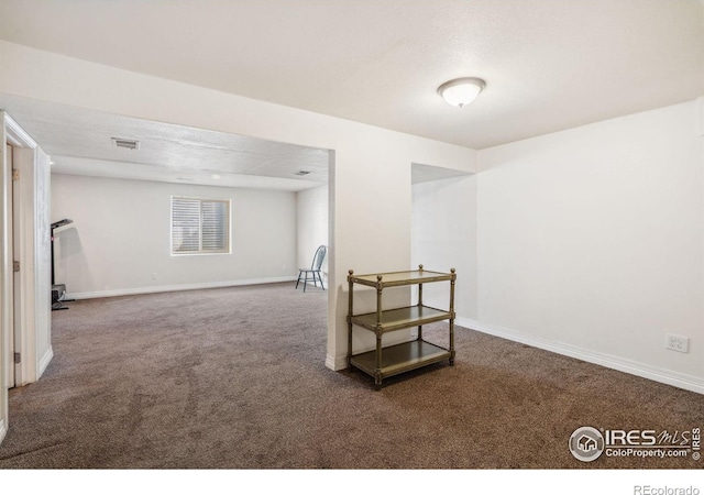 basement featuring visible vents, baseboards, and carpet