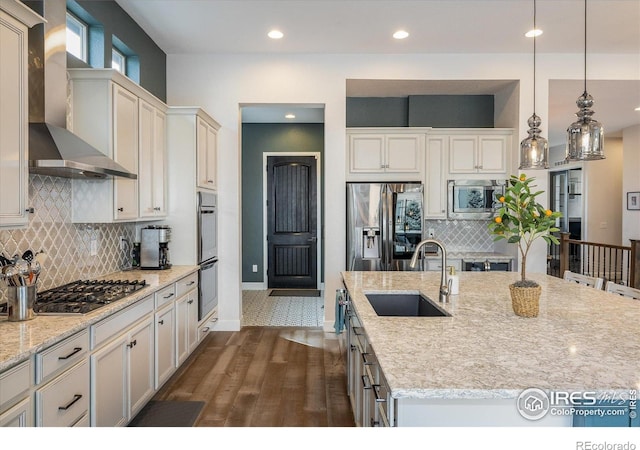 16392 Spanish Peak Way, Broomfield, CO 80023 - kitchen with appliances with stainless steel finishes, a sink, wall chimney exhaust hood, dark wood finished floors, and decorative backsplash