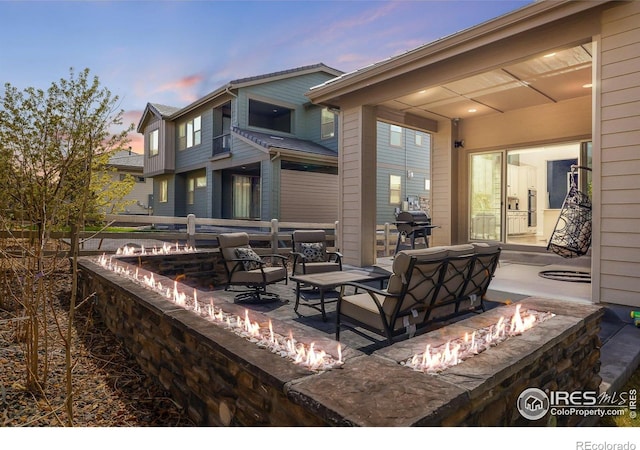 16392 Spanish Peak Way, Broomfield, CO 80023 - patio terrace at dusk featuring area for grilling and an outdoor living space with a fire pit