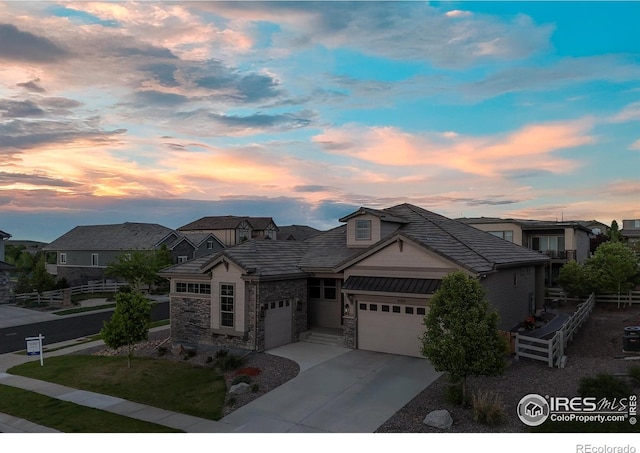16392 Spanish Peak Way, Broomfield, CO 80023 - view of front of house featuring fence, an attached garage, stone siding, and driveway