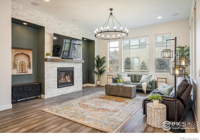 16392 Spanish Peak Way, Broomfield, CO 80023 - living area featuring wood finished floors, a chandelier, a stone fireplace, and baseboards