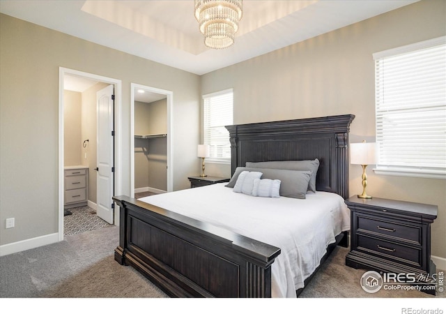 16392 Spanish Peak Way, Broomfield, CO 80023 - carpeted bedroom featuring a chandelier, baseboards, a walk in closet, connected bathroom, and a tray ceiling