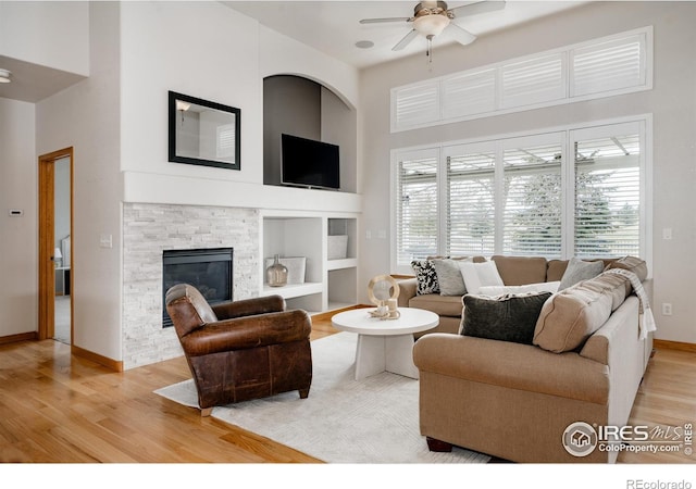 6771 Crooked Stick Dr, Windsor, CO 80550 - living area with light wood-type flooring, a towering ceiling, ceiling fan, built in shelves, and baseboards