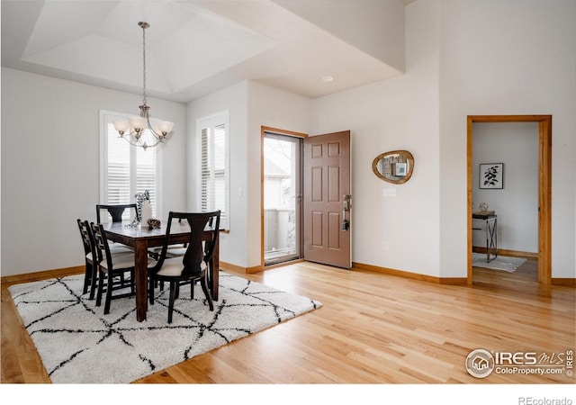 6771 Crooked Stick Dr, Windsor, CO 80550 - dining space featuring a raised ceiling, light wood-style floors, a chandelier, and baseboards