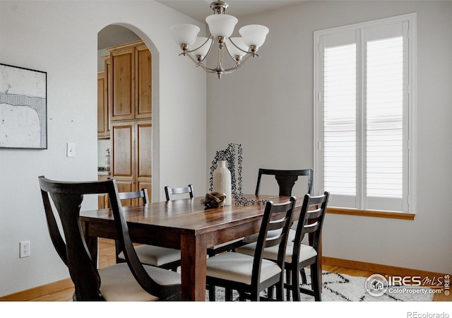 6771 Crooked Stick Dr, Windsor, CO 80550 - dining room with arched walkways, a chandelier, baseboards, and light wood-style flooring