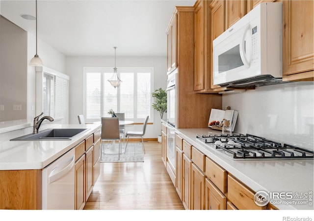 6771 Crooked Stick Dr, Windsor, CO 80550 - kitchen featuring white appliances, light wood finished floors, a sink, light countertops, and hanging light fixtures