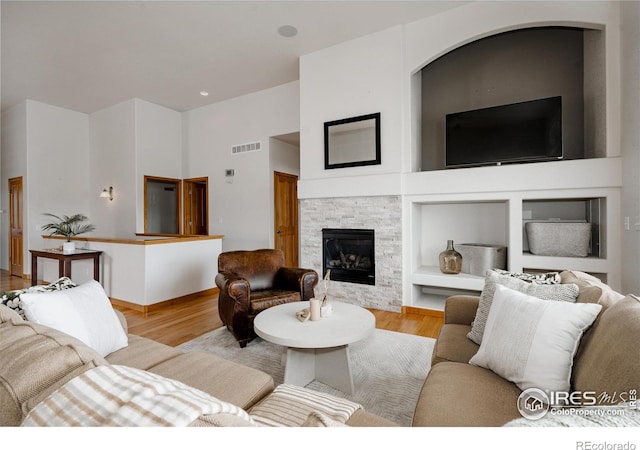 6771 Crooked Stick Dr, Windsor, CO 80550 - living room featuring wood finished floors, built in shelves, a fireplace, and a high ceiling