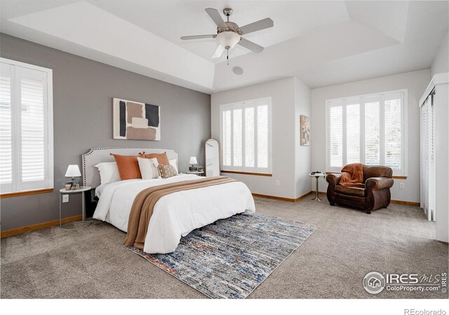 6771 Crooked Stick Dr, Windsor, CO 80550 - carpeted bedroom featuring a tray ceiling, baseboards, and a ceiling fan