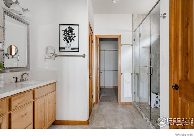 6771 Crooked Stick Dr, Windsor, CO 80550 - full bath with a stall shower, vanity, baseboards, and a spacious closet
