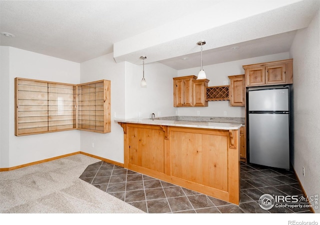6771 Crooked Stick Dr, Windsor, CO 80550 - kitchen featuring freestanding refrigerator, a kitchen bar, a peninsula, baseboards, and hanging light fixtures