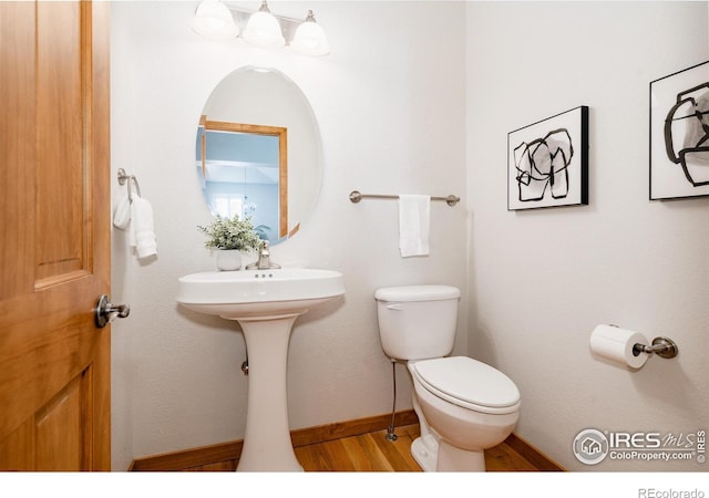 6771 Crooked Stick Dr, Windsor, CO 80550 - half bathroom with toilet, wood finished floors, and baseboards