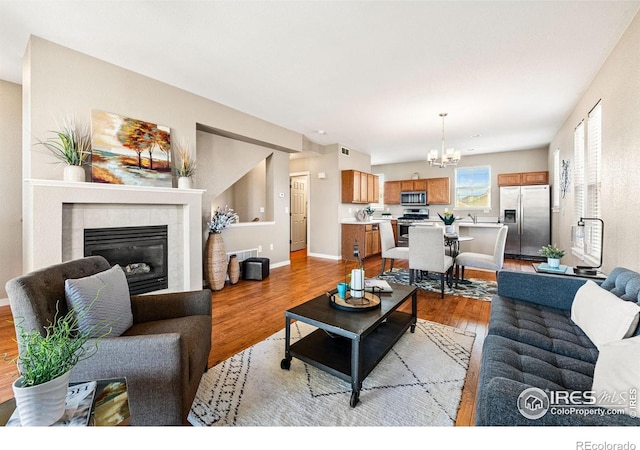 658 Casper Dr, Lafayette, CO 80026 - living room with a chandelier, light wood finished floors, a fireplace, and baseboards