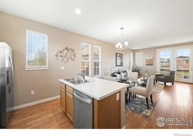 658 Casper Dr, Lafayette, CO 80026 - kitchen featuring stainless steel appliances, a sink, a chandelier, open floor plan, and light wood-type flooring