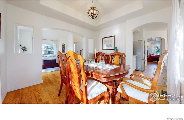 5105 Nelson Ct, Fort Collins, CO 80528 - dining room with a tray ceiling, arched walkways, and light wood finished floors