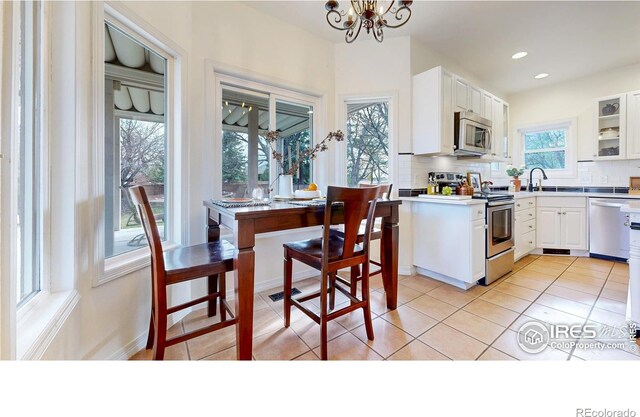 5105 Nelson Ct, Fort Collins, CO 80528 - kitchen with white cabinetry, light tile patterned flooring, light countertops, stainless steel appliances, and backsplash