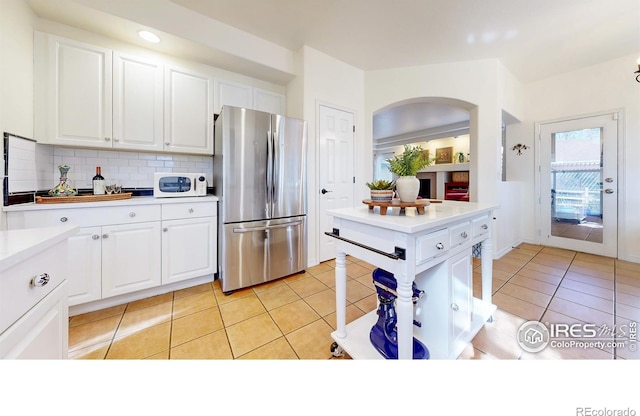 5105 Nelson Ct, Fort Collins, CO 80528 - kitchen with white microwave, freestanding refrigerator, white cabinetry, light countertops, and backsplash