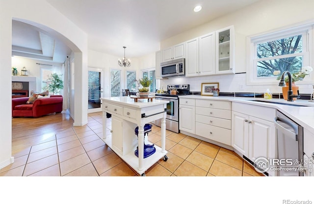 5105 Nelson Ct, Fort Collins, CO 80528 - kitchen featuring a chandelier, glass insert cabinets, white cabinetry, appliances with stainless steel finishes, and a sink