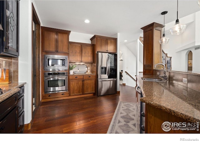 7225 Royal Country Down Dr, Windsor, CO 80550 - kitchen featuring stainless steel appliances, a sink, backsplash, dark stone counters, and recessed lighting