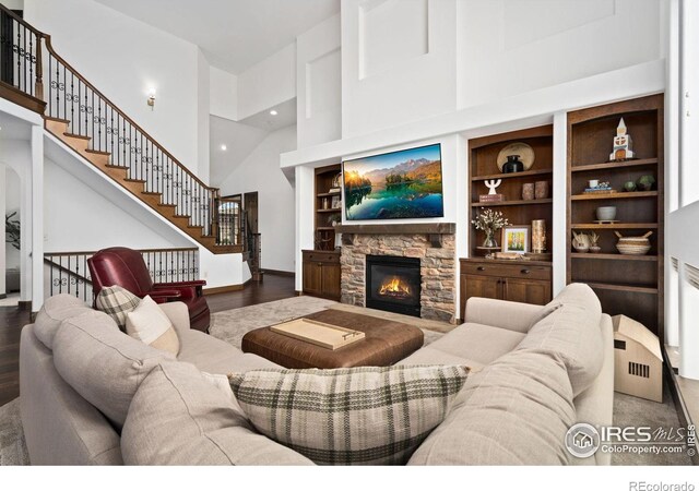 7225 Royal Country Down Dr, Windsor, CO 80550 - living area featuring high vaulted ceiling, a fireplace, stairway, wood finished floors, and built in features