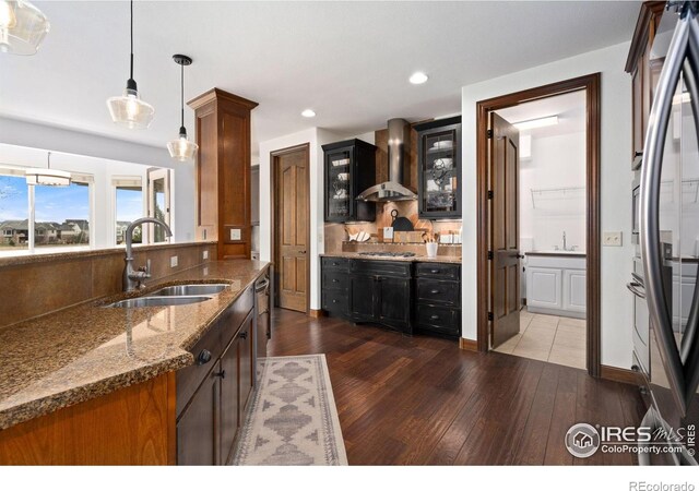 7225 Royal Country Down Dr, Windsor, CO 80550 - kitchen with wall chimney exhaust hood, a sink, hardwood / wood-style flooring, dark stone counters, and glass insert cabinets