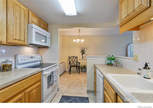 kitchen with light countertops, backsplash, a sink, and white appliances