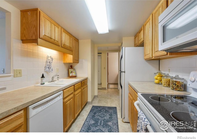kitchen with a sink, backsplash, light countertops, and white appliances