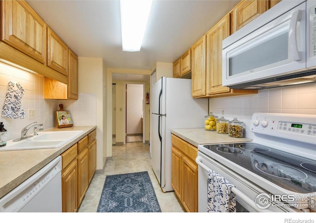 kitchen with light countertops, backsplash, a sink, and white appliances