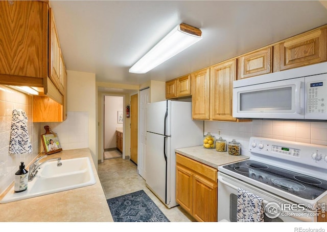 kitchen featuring a sink, light countertops, tasteful backsplash, and white appliances