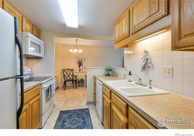 kitchen featuring a notable chandelier, white appliances, light countertops, backsplash, and a sink