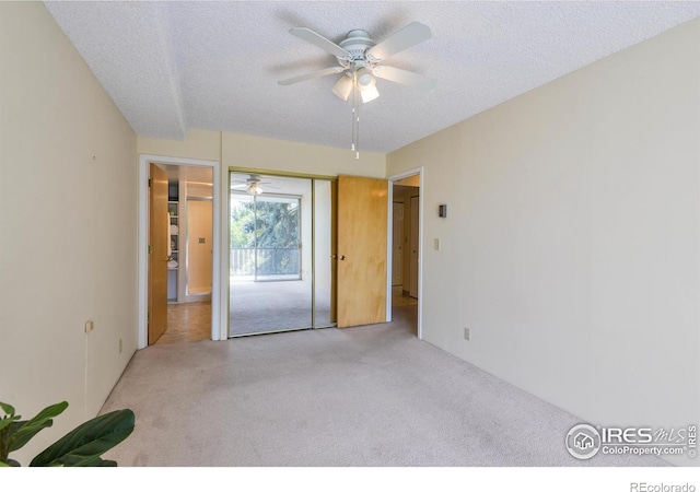 empty room with a textured ceiling, ceiling fan, and carpet floors